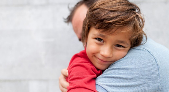 A young boy is hugging his father.